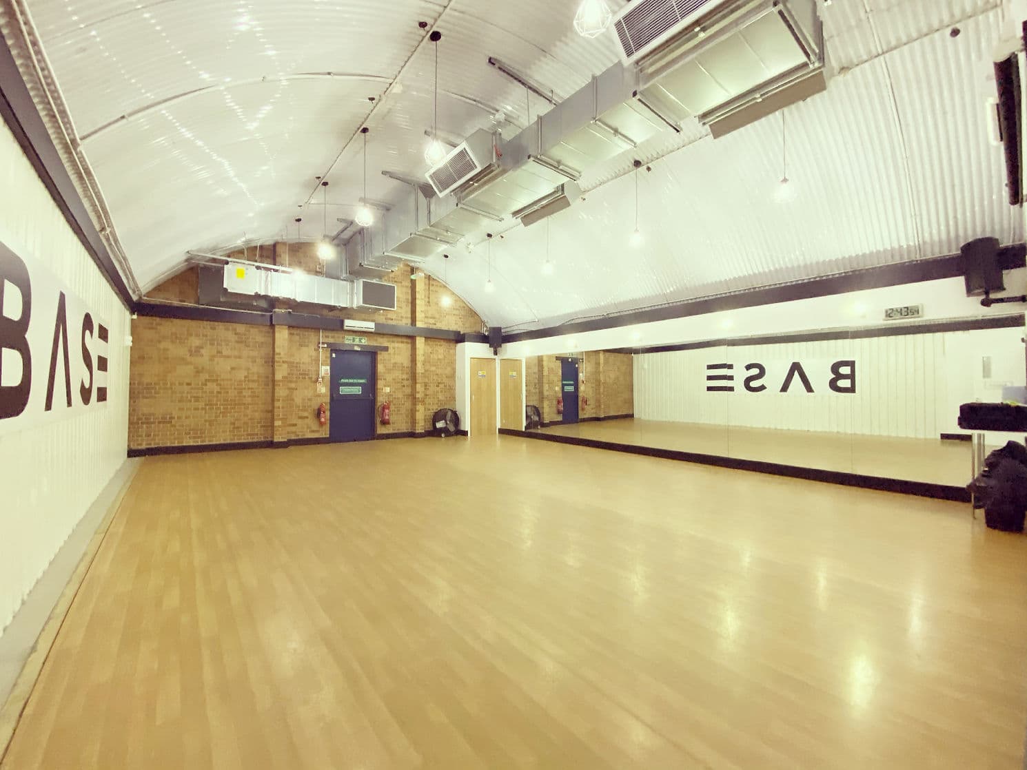 A wide, light-filled BASE studio with the BASE wordmark on the wall and a Harlequin sprung floor