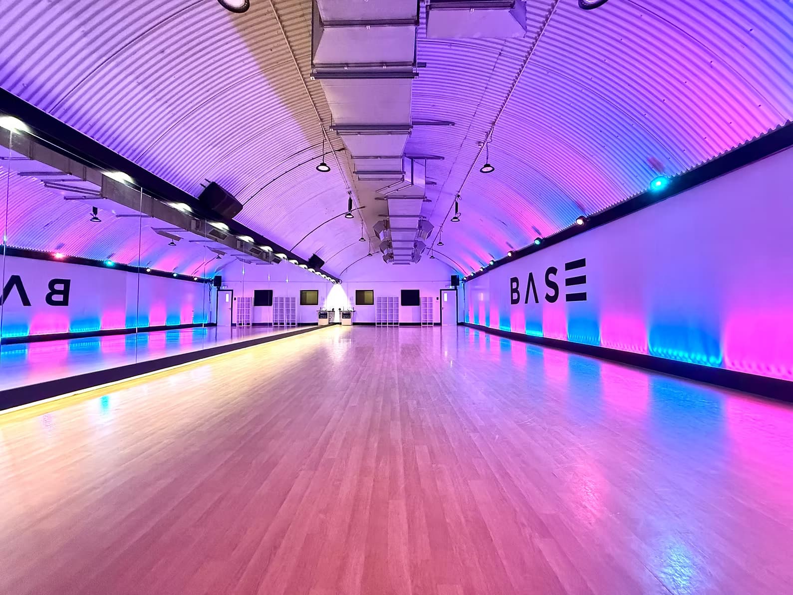A BASE studio washed in pink and blue light, mirrors along one wall and a Harlequin sprung floor