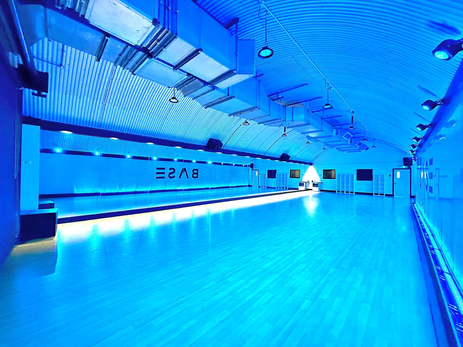 A BASE studio lit in deep blue, mirrors and sprung floor running the length of the room